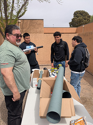 Three students working on a rocket